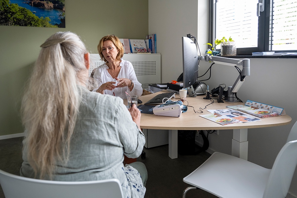 Menopause care Forest Hill, A woman sitting at a desk with another woman beside her, both engaged in conversation